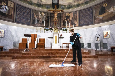 Señora operaria de limpieza, limpiando el suelo con una mopa en una iglesia.